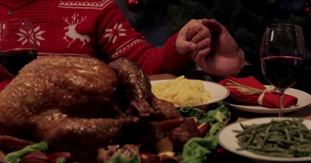cropped view of wife and husband taking hands for praying on Thanksgiving Day, baked turkey on festive table - Footage, Video
