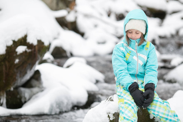 κορίτσι ανάπαυσης σε έναν βράχο ενός καταρράκτη του χειμώνα - Φωτογραφία, εικόνα