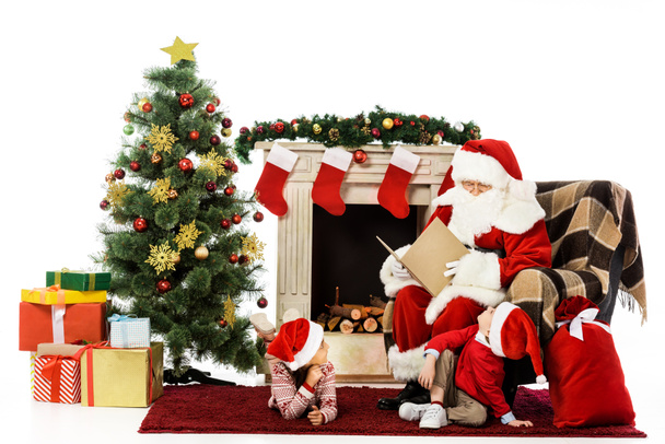 happy kids and santa relaxing in front of fireplace isolated on white - Foto, imagen