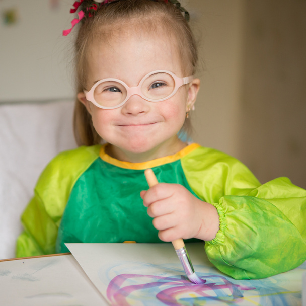 Девушка с синдромом Дауна, покрытая краской при рисовании - Фото, изображение