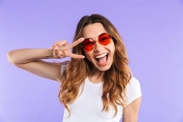 Photo of amazing happy cute woman isolated over purple wall background showing peace gesture. - Фото, изображение