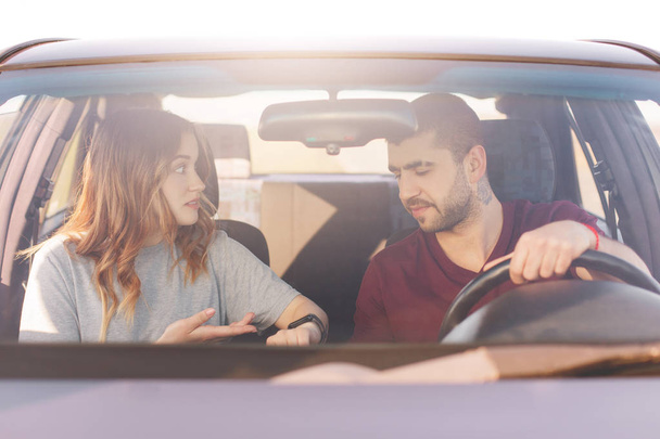 Nervous female indicates at watch, shows it husband, warns that they are late for meeting, stand in traffic jam while drive in car. Family couple hurry for birthday party, pose in automobile - Fotoğraf, Görsel