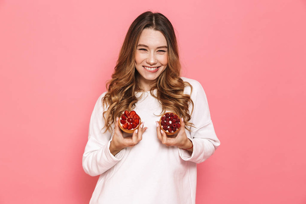 Portrait of a satisfied young woman showing pastry isolated over pink background - Foto, Bild