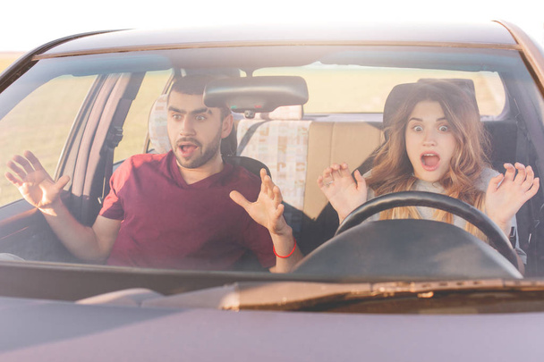 Danger on road. Mad young woman and man have car crash, looks in terror in windscreen. Depressed female can`t control movement and driving. Scared family couple see accident, stare at camera - Foto, Imagen