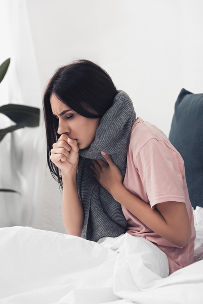 sick young woman sitting in bed and having cough - Photo, Image