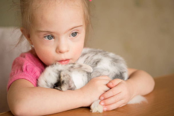 Girl with Down syndrome hugs the rabbit - Photo, Image