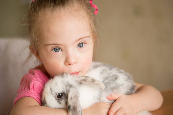 Mädchen mit Down-Syndrom umarmt Kaninchen - Foto, Bild