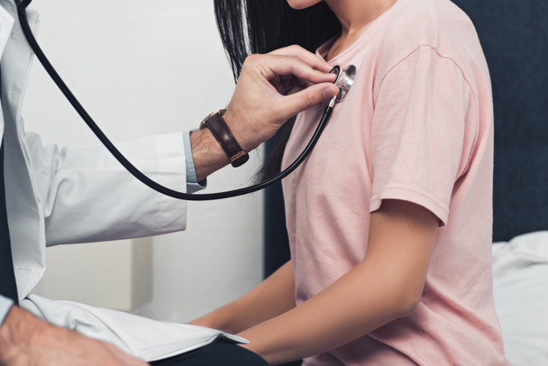 bijgesneden schot van arts luisteren adem van vrouwelijke patiënt - Foto, afbeelding