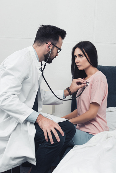 confident young doctor listening breath of female patient - Foto, Imagen