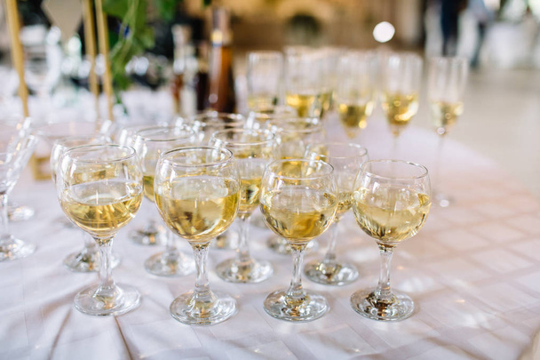 tabel instellen, glazen met mousserende wijn. champagneglazen close-up. Feestelijke tafel setting met champagne. - Foto, afbeelding