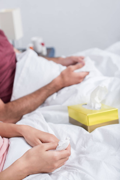 cropped shot of sick couple sitting in bed with box of paper napkins - Foto, Imagem