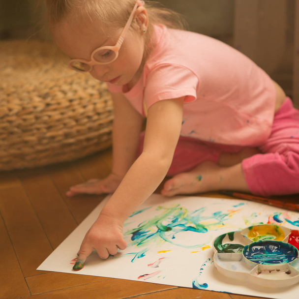 Meisje met Down syndroom bedekt met verf bij het tekenen - Foto, afbeelding