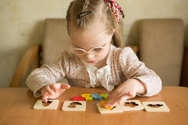 intelligente ragazza con sindrome di Down raccoglie puzzle
 - Foto, immagini