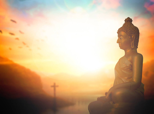 Religionskonzept: Buddha-Statue und Kreuz vor Sonnenuntergang - Foto, Bild