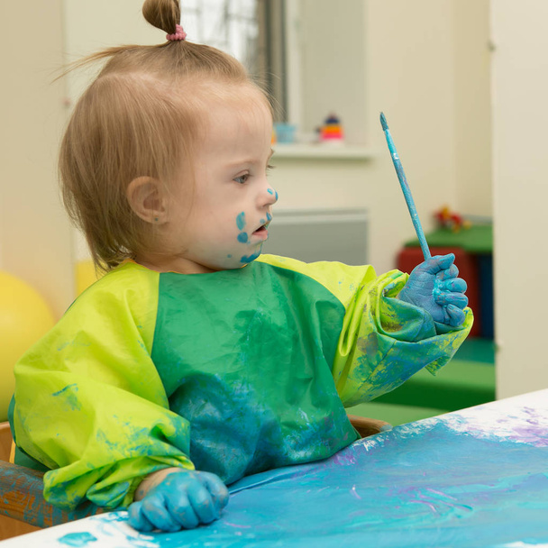Κορίτσι με σύνδρομο Down καλύπτονται με χρώμα κατά τη σχεδίαση - Φωτογραφία, εικόνα