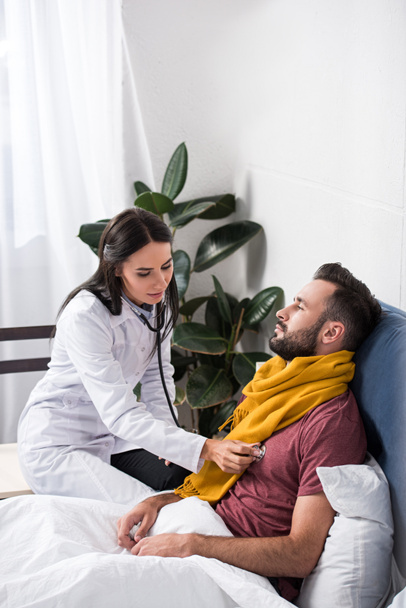 femme médecin en utilisant stéthoscope pour écouter les patients respirer alors qu'il est couché dans le lit
 - Photo, image