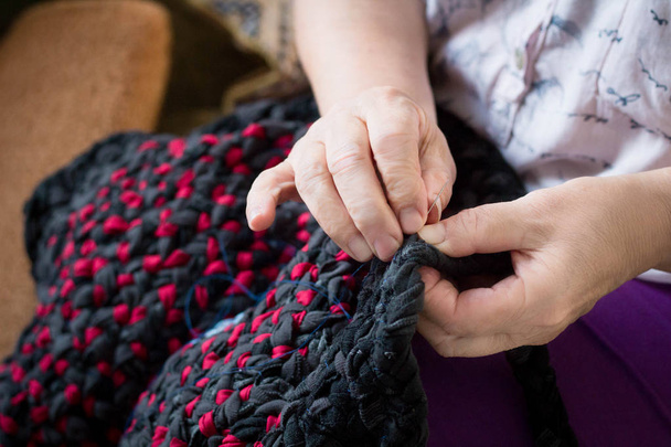 Primer plano de señora anciana haciendo costura trabajo a mano con aguja e hilo
 - Foto, imagen
