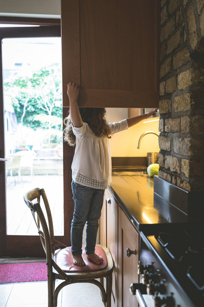 Dziewczyna szuka jedzenie w kuchni w domu - Zdjęcie, obraz