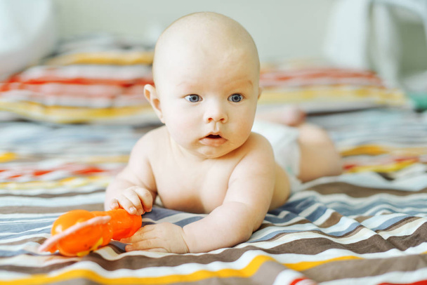 baby with toy laying on the tummy in bedroom - Foto, Imagem