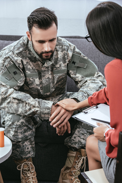 female psychiatrist supporting depressed soldier with post traumatic syndrome during therapy session - Photo, Image