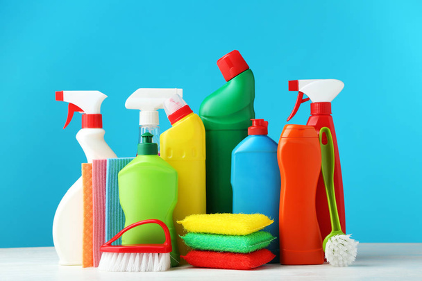 Bottles with detergent and cleaning tools on blue background - Fotoğraf, Görsel
