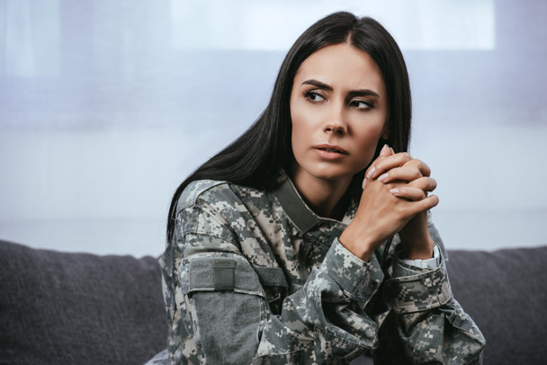 макро портрет вдумливі жінка-солдат в з ПТСР, сидячи на дивані і дивитися вбік Ремені офіцерські - Фото, зображення