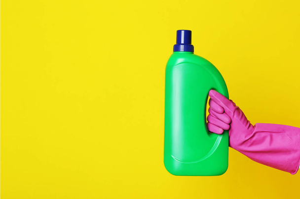 human hand holding bottle with detergent on yellow background - Foto, immagini