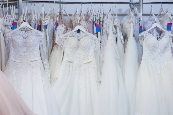 Gyönyörű esküvői ruha lógott egy rack a boltban. - Fotó, kép