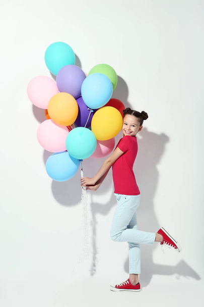 Όμορφη νεαρή κοπέλα με χρωματιστά μπαλόνια σε λευκό φόντο - Φωτογραφία, εικόνα