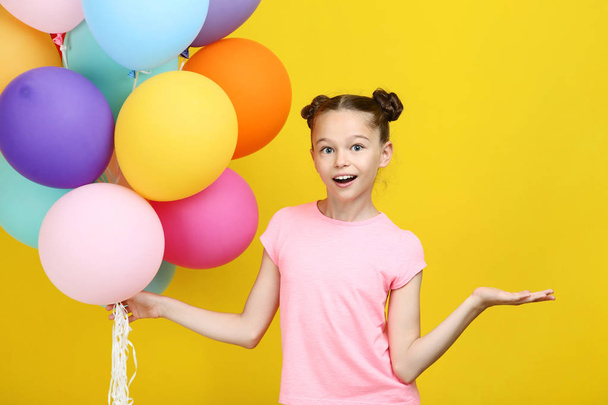 Beautiful young girl with colored balloons on yellow background - Foto, Imagen