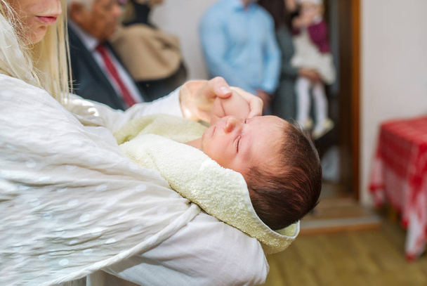 子供の洗礼。母親が洗礼の儀式の中に彼女の手の子を保持しています。. - 写真・画像