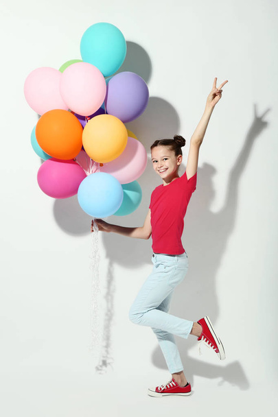 Beautiful young girl with colored balloons on white background - Photo, Image
