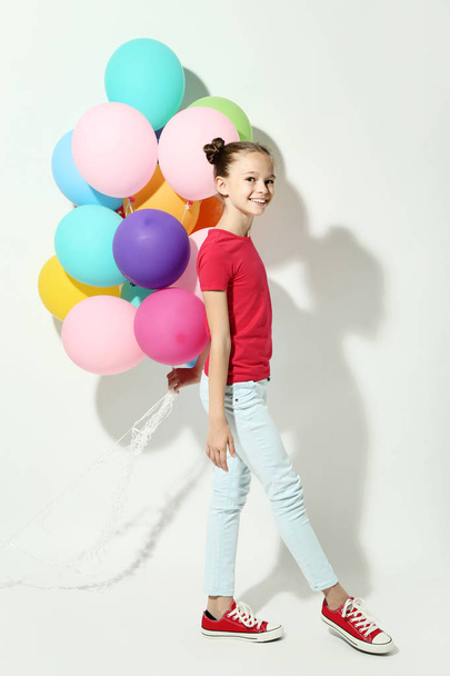 Beautiful young girl with colored balloons on white background - 写真・画像