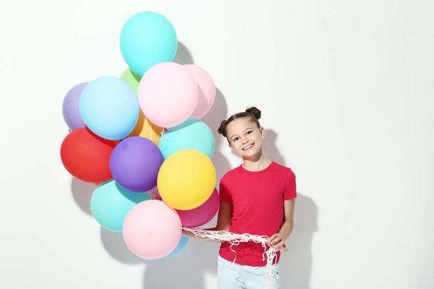 Beautiful young girl with colored balloons on white background - Фото, зображення