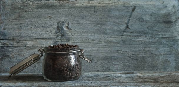 Roasted coffee beans in glass jars on wood table - 写真・画像