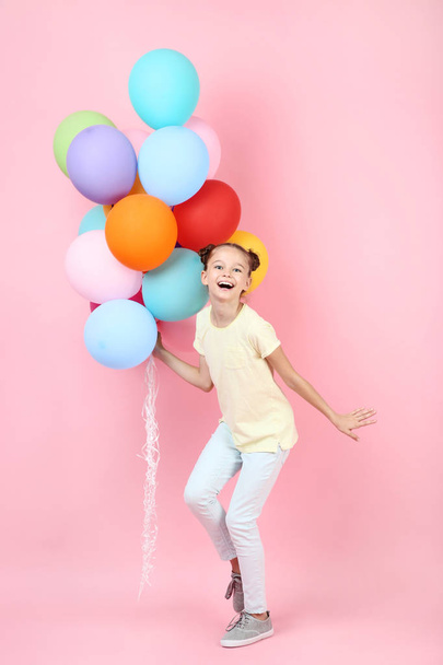 Cute young girl with colored balloons on pink background - Foto, imagen