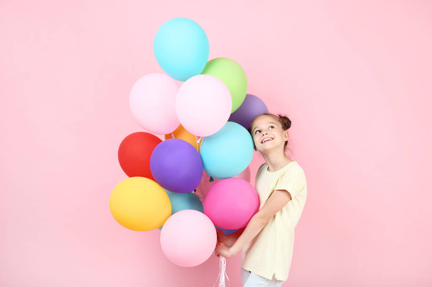 Cute young girl with colored balloons on pink background - Foto, Imagem