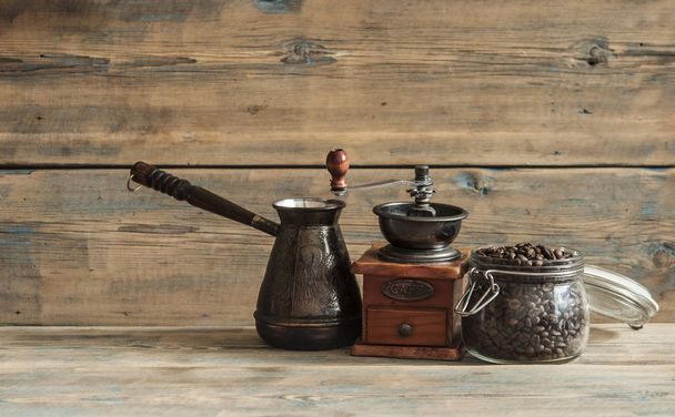 Grains de café torréfiés dans un bocal en verre, moulin à café et jezva sur table en bois
 - Photo, image