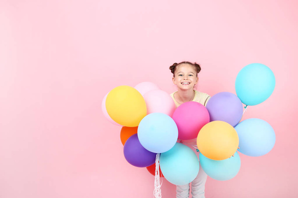 Cute young girl with colored balloons on pink background - Foto, afbeelding