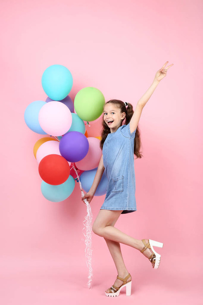 Young girl with colored balloons on pink background - 写真・画像