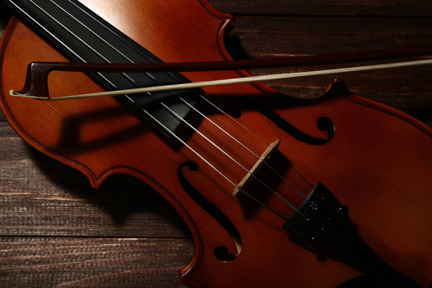 Violin with bow on brown wooden background - Foto, imagen