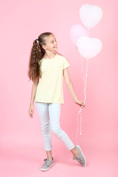 Cute young girl with balloons on pink background - Фото, изображение