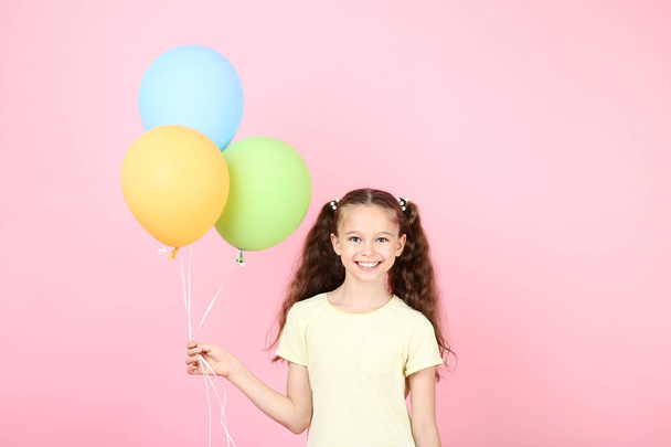 Cute young girl with colored balloons on pink background - Фото, изображение