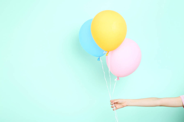 Female hand holding colorful balloons on mint background - Foto, afbeelding