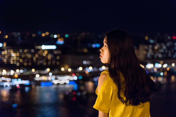Dziewczyna cieszy widok na miasto z góry w nocy - Zdjęcie, obraz