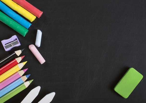 School supplies on blackboard with empty surface. Plasticine, chalk, sharpener, crayons and eraser. - Zdjęcie, obraz