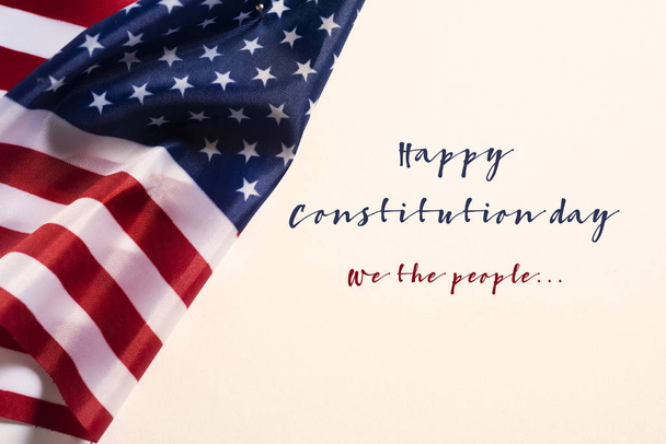 primer plano de una bandera de los Estados Unidos y el texto feliz día de la constitución sobre un fondo blanquecino
 - Foto, imagen
