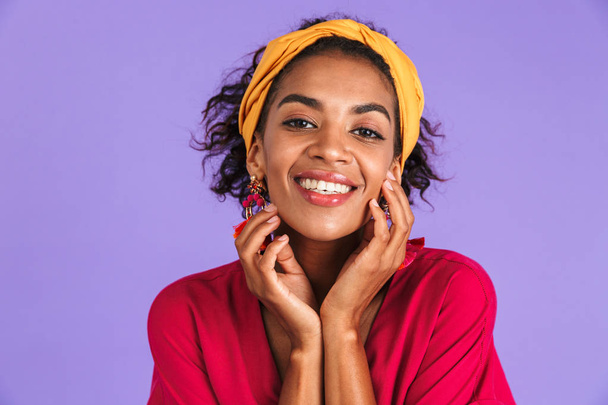 Portrait of a smiling young african woman in headband standing over violet background - Fotó, kép