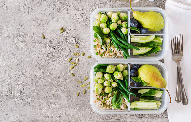 Envases de preparación de comida verde vegana con arroz, judías verdes, coles de Bruselas, pepino y frutas sobre fondo gris hueso
 - Foto, Imagen