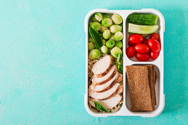 Recipientes de preparação de refeição verde saudável com filé de frango, arroz, couves de bruxelas e legumes no fundo de pedra azul
 - Foto, Imagem
